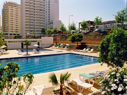 a swimming pool with lounge chairs and a building at Apartamentos Jardins da Rocha in Portimão