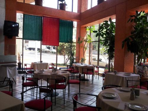 ein Restaurant mit Tischen und Stühlen in einem Zimmer mit Fenstern in der Unterkunft Hotel Inn Sur in Mexiko-Stadt