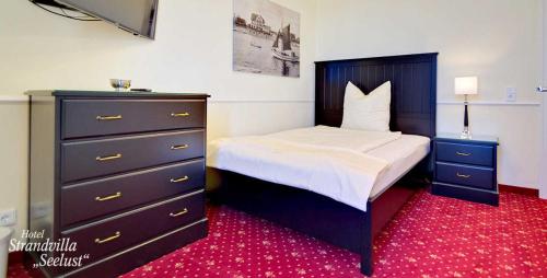 a bedroom with a large bed and a dresser at Strandvilla Seelust in Schönberger Strand