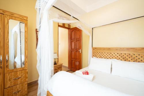 
a hotel room with a bed and a dresser at Rayan Apartments & Safaris in Arusha
