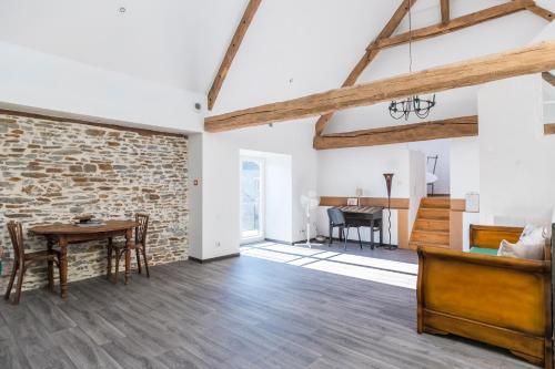 - un salon avec un mur en briques, une table et des chaises dans l'établissement Les Colombes de la Baie du Mont Saint-Michel, à Aucey-la-Plaine