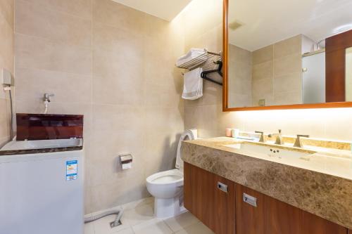 a bathroom with a toilet and a sink and a mirror at Sanya Yikehai View Apartments in Sanya