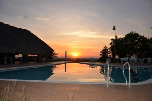 a swimming pool with a sunset in the background at Hotel Campestre Luna Roja in Puerto López