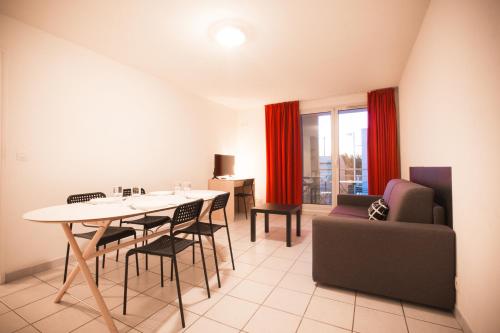 een woonkamer met een tafel en stoelen en een bank bij City Résidence Avignon (5 Epi) in Avignon