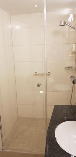 a shower with a glass door next to a sink at Akzent Hotel Gut Höing in Unna