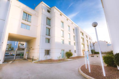 a white building with a street light in front of it at City Résidence Avignon in Avignon