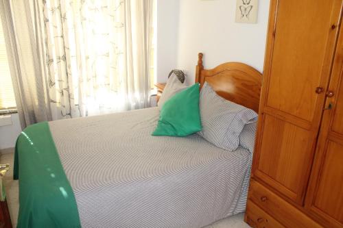 a bedroom with a bed with green and white pillows at La Posada de Mijas in Mijas