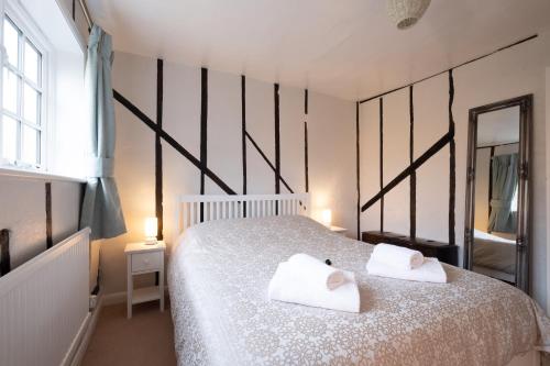 a bedroom with a bed with two towels on it at Bay Cottage in Thorpeness