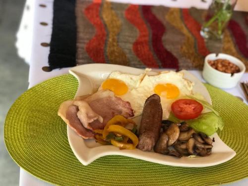 un plato de comida con salchichas, huevos y setas en Beverly Corner Lodge en Matatiele