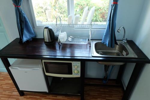 a kitchen counter with a microwave and a sink at Saengcha Farm Resort in Prachin Buri