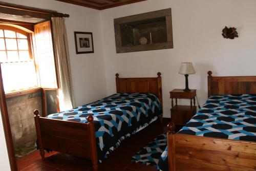 a bedroom with a bed with a blue and white comforter at Quinta dos Figos "5 Trevos GOLD" in Praia da Vitória