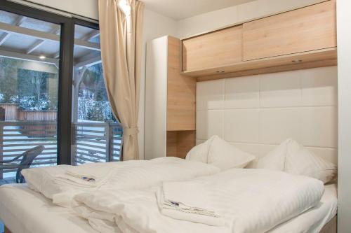 a bedroom with two white beds and a balcony at Pension Schizentrum Grosseck - Speiereck in Mauterndorf