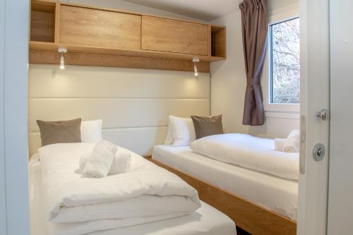two beds in a room with white sheets at Pension Schizentrum Grosseck - Speiereck in Mauterndorf