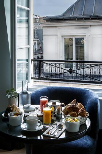 a table with breakfast food on top of a balcony at Maison Armance - Esprit de France in Paris