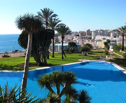 una gran piscina azul con palmeras y el océano en Castillo de Santa Clara Luxury, en Torremolinos