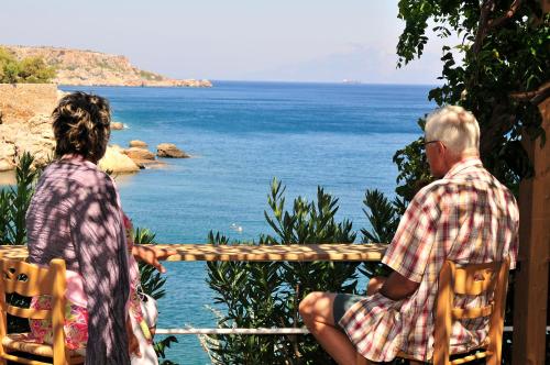 two people sitting on chairs looking at the ocean at Marina Hotel in Agios Kirykos