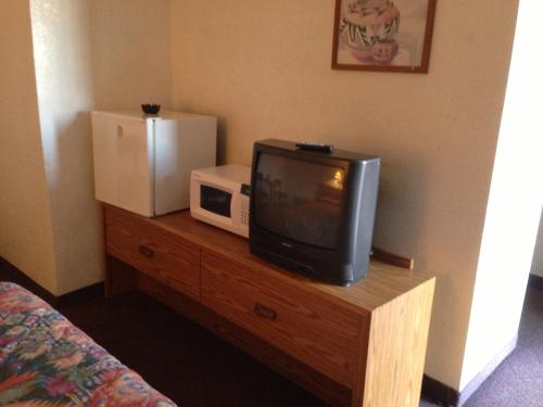 TV y mesa de madera con microondas. en National 9 Inn Sand Canyon, en Cortez