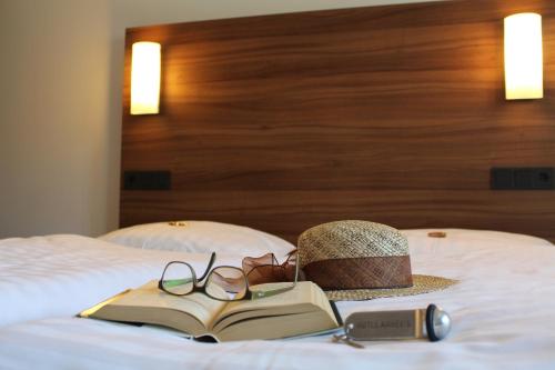a hat and glasses and a book on a bed at Hotel garni Anger 5 in Bad Frankenhausen