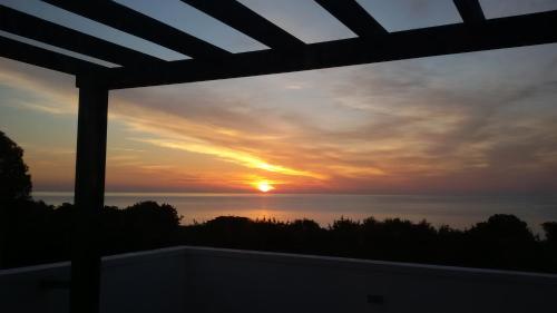 ein Sonnenuntergang von einem Balkon mit Blick auf das Meer gesehen in der Unterkunft Beachfront Villa SeaShell Superior in Gennadi