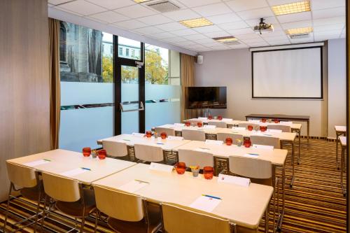 a conference room with tables and chairs and a screen at Ibis Brussels City Centre in Brussels