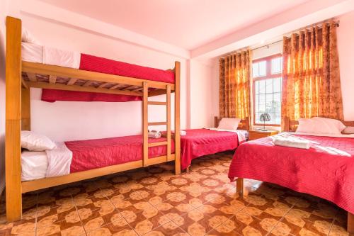 two bunk beds in a room with red sheets at Paracas Hotel Ballestas Island in Paracas