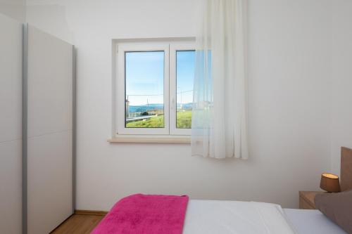 een slaapkamer met een bed en een raam bij Apartments Vuković in Podstrana