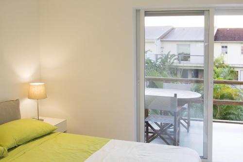 a bedroom with a bed and a balcony with a table at Beach House Antigua in Jolly Harbour