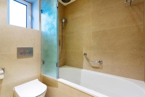 a bathroom with a tub and a toilet and a shower at Veeve - Mews and Majesty in Mayfair in London