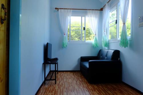 a living room with a black couch and a window at Saengcha Farm Resort in Prachin Buri