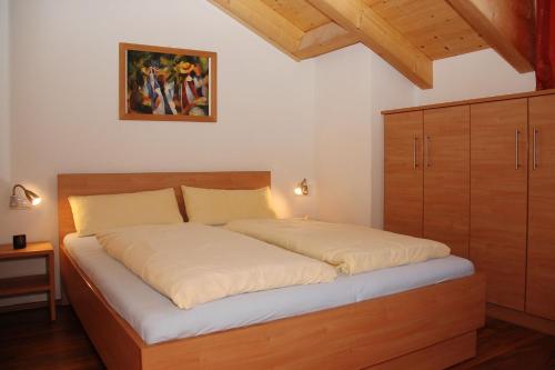 ケーニヒスライテンにあるFerienwohnungen Langのベッドルーム1室(大型ベッド1台、木製ヘッドボード付)