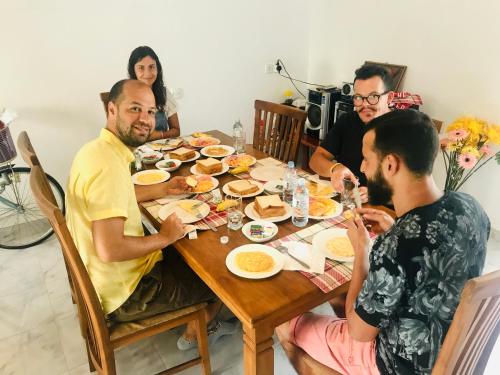 a group of people sitting around a table eating food at White Villa Airport Transit Hotel in Katunayake