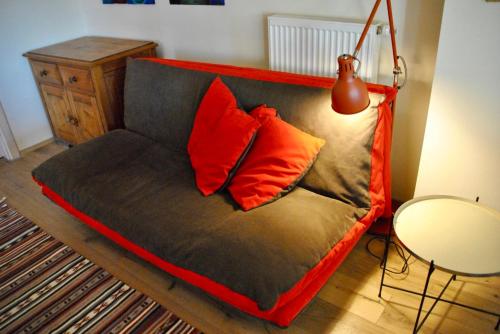 a couch with red pillows in a living room at Kranichhof - Studio, Loft & Atelier in Zossen