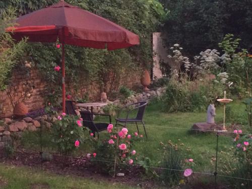 a garden with a red umbrella and chairs and flowers at Kranichhof - Studio, Loft & Atelier in Zossen