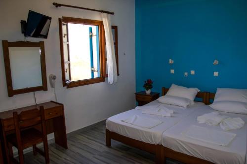 a bedroom with two beds and a mirror and a window at Ioanna Rooms in Naousa