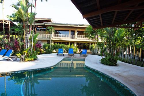 a swimming pool with two blue chairs next to a building at Arenal Backpackers Resort in Fortuna