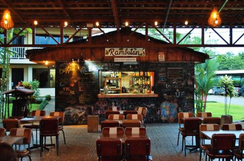 un restaurante con un bar con mesas y sillas en Arenal Backpackers Resort en Fortuna