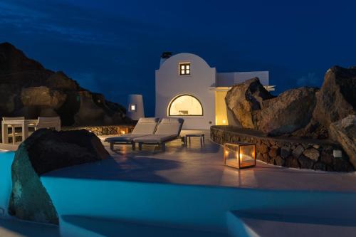 a night view of a patio with chairs and a table at Aenaon Villas in Imerovigli