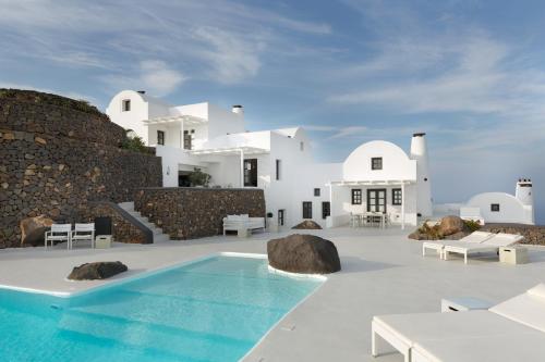 a villa with a swimming pool in front of a building at Aenaon Villas in Imerovigli