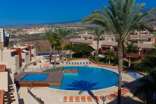 - une vue sur la piscine bordée de palmiers et de bâtiments dans l'établissement Paraiso II SS FREE WIFI, à Playa Paraiso