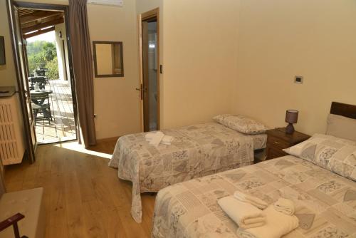 a hotel room with two beds and a balcony at Agriturismo Ai Prüsot in Bagnolo Piemonte