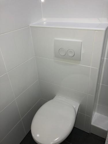 a white toilet in a white tiled bathroom at Apartment 4 Rent in Bochum
