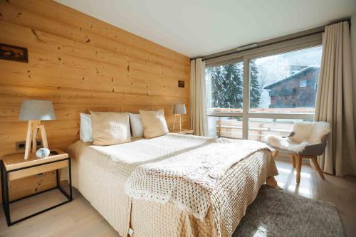 um quarto com uma cama e uma grande janela em Mègeve - Luxury appartment – AE302 em Megève