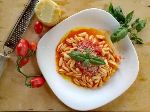 a white bowl of pasta with tomato sauce and basil at Agriturismo La Palazza in Sala Consilina