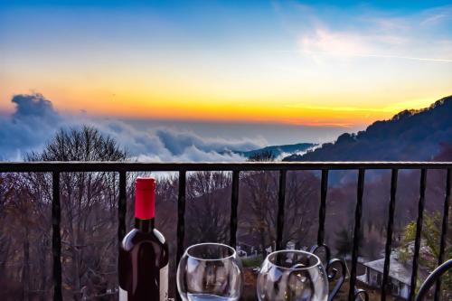 a bottle of wine and glasses on a balcony with the sunset at Tasia Mountain Hotel in Chania
