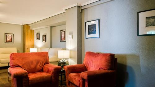 a living room with two orange chairs and a couch at Hotel La Rambla in Biescas