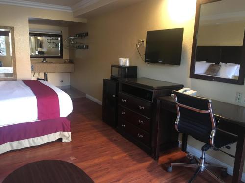 サンバーナーディーノにあるBudget Lodge San Bernardinoのベッド、デスク、テレビが備わるホテルルームです。