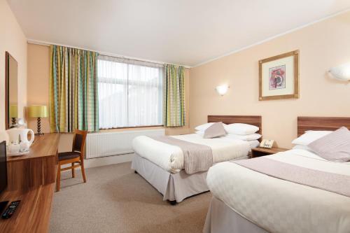 a hotel room with two beds and a desk at Alma Lodge Hotel in Stockport