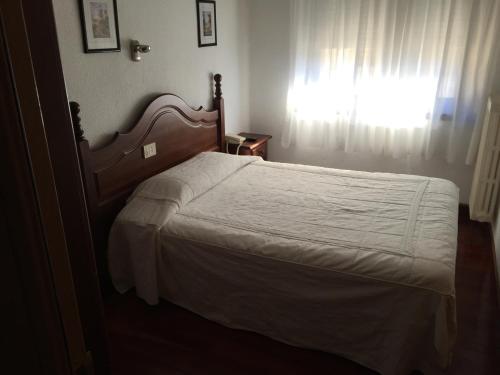 a bedroom with a bed with a white bedspread and a window at Hotel La Rambla in Biescas