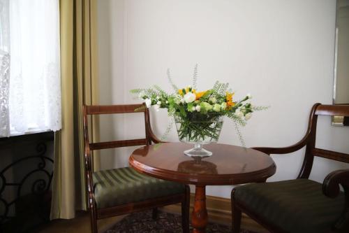 a vase of flowers sitting on a table with two chairs at Hotel butikowy Pałac Jabłonna in Jabłonna