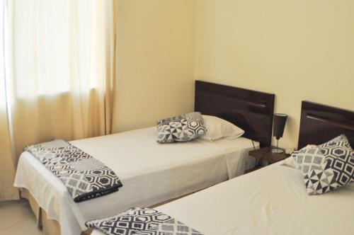 a bedroom with two beds with pillows on them at Garzota Suites Airport Balcony in Guayaquil